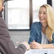 A counselor smiles at her client who is sitting across the desk.